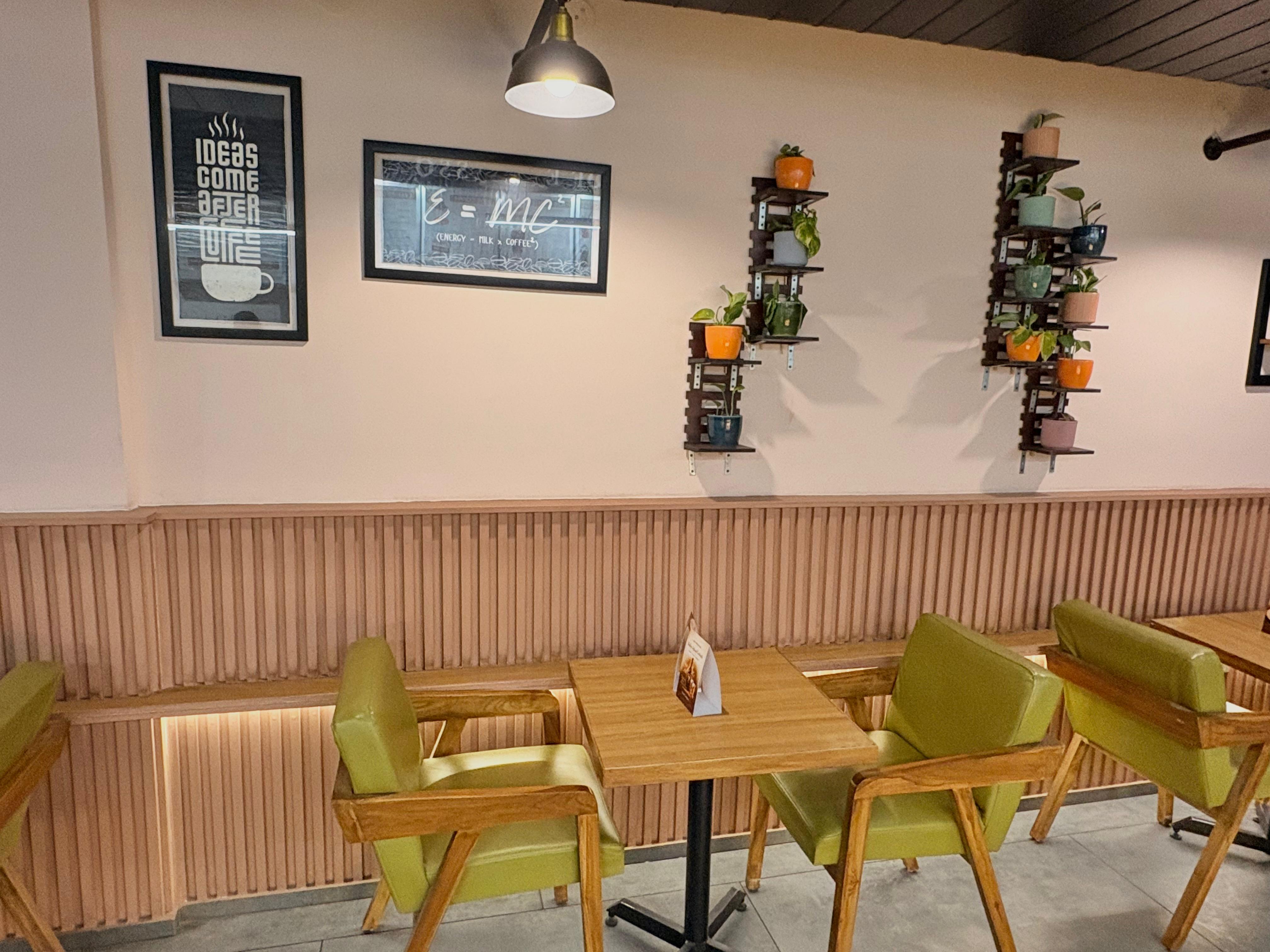 Green banquette chairs, plant shelves, and the chalk physics sign