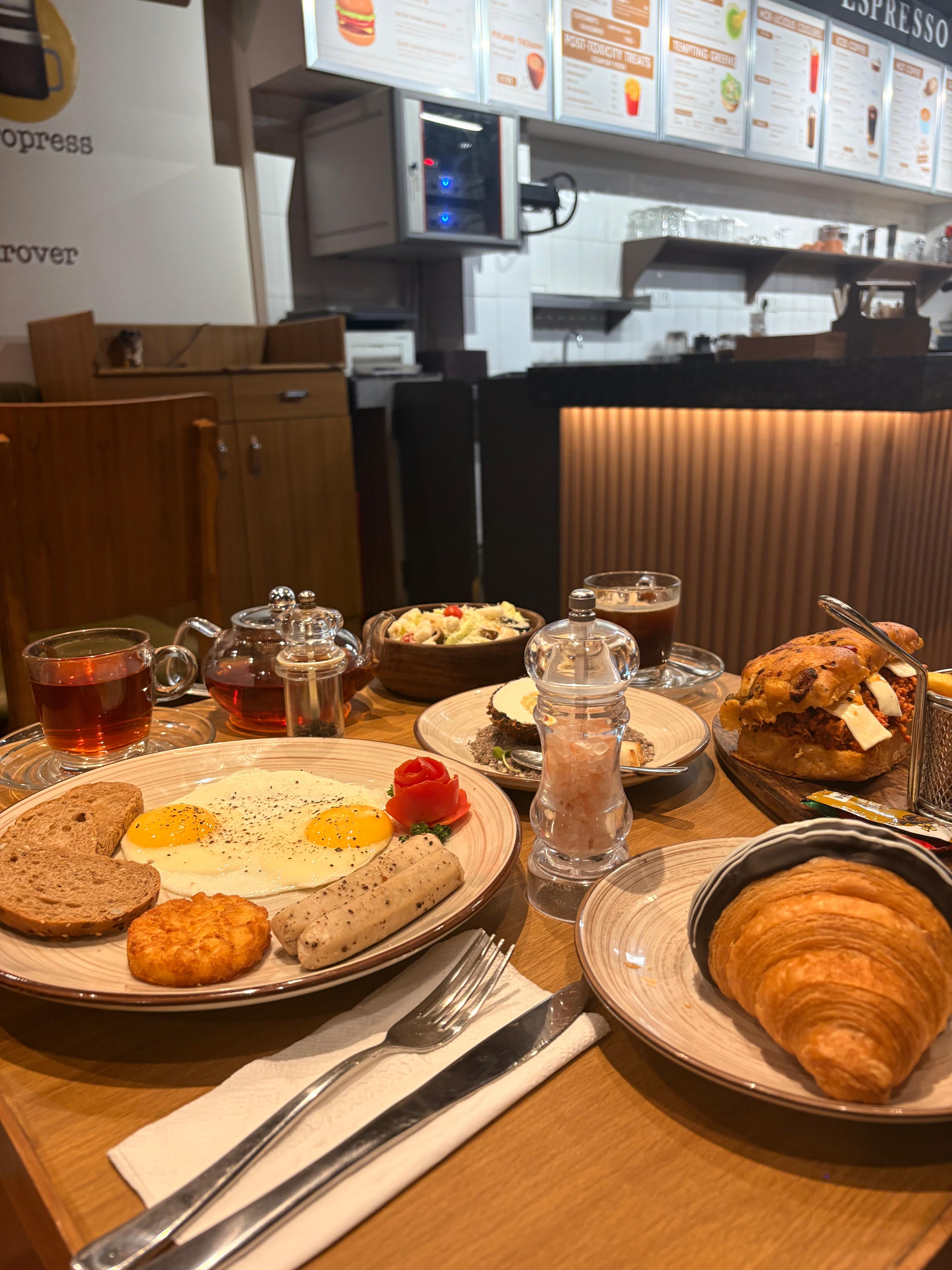 All-day breakfast plate with eggs, sausage, croissant, tea